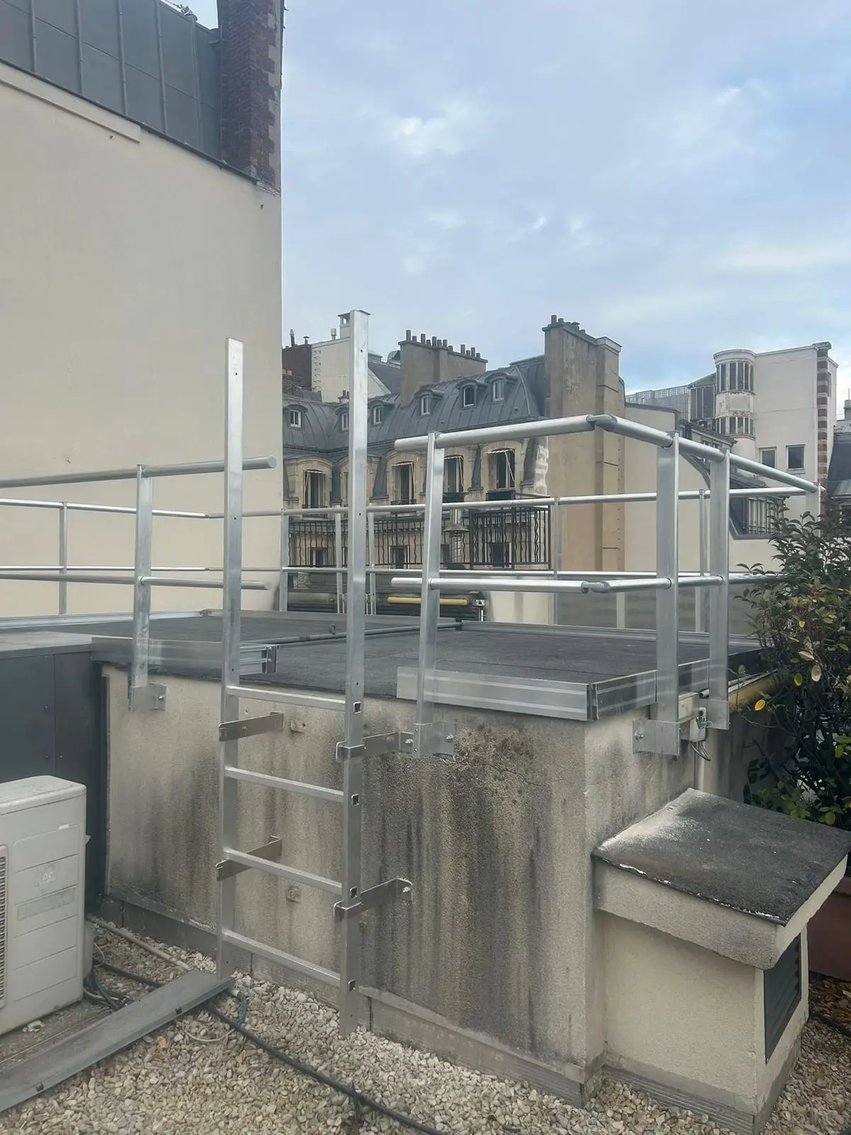 Échelle d'accès et garde-corps installés sur un acrotère en toiture parisienne