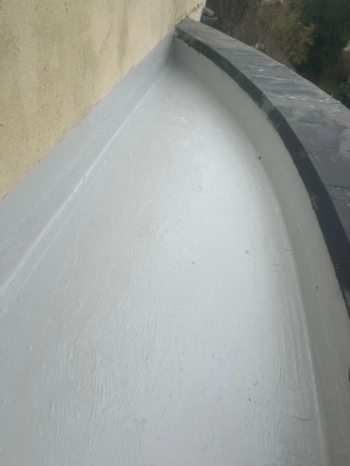 Après travaux : le même balcon étanché en résine grise, relevés compris
